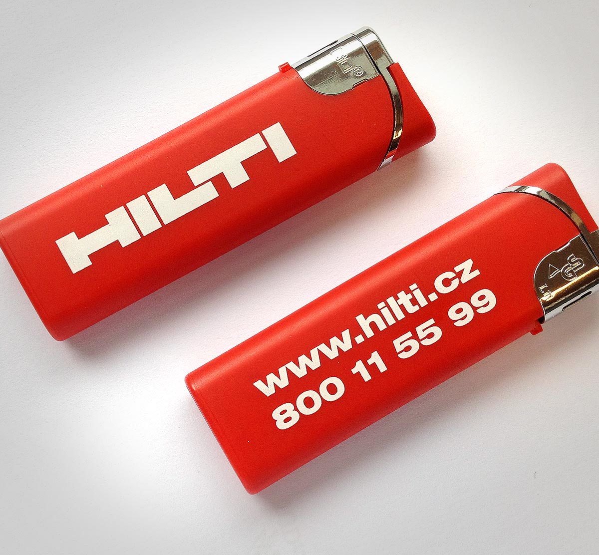 Reklamní červené zapalovače s potiskem loga Hilti a kontaktem