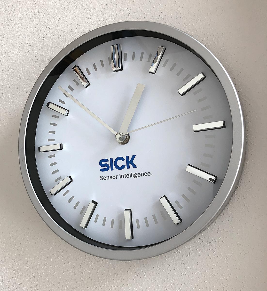 Reklamní nástěnné hodiny ve stříbrném rámu s potiskem loga SICK Sensor Intelligence