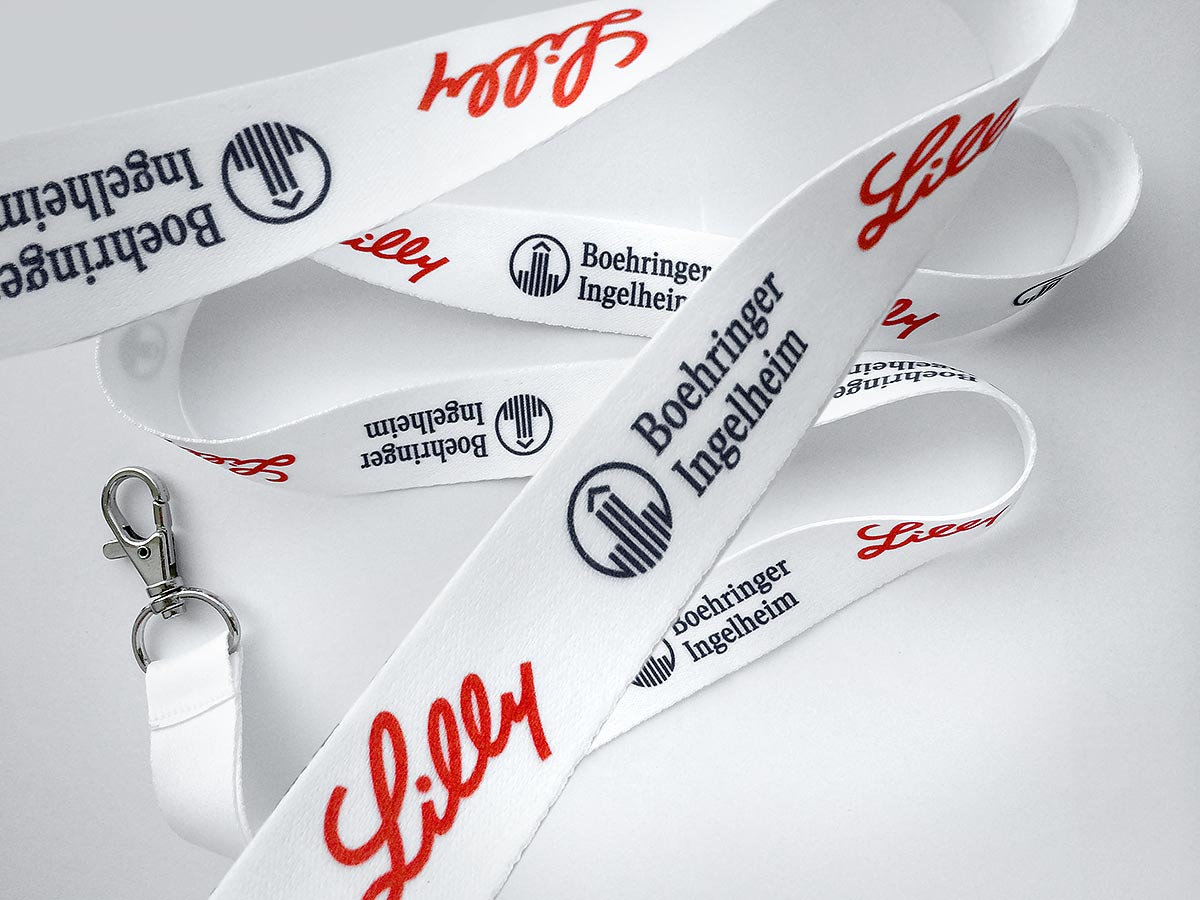 Reklamní bílé šňůrky na krk s karabinou a potiskem loga Lilly a Boehringer Ingelheim