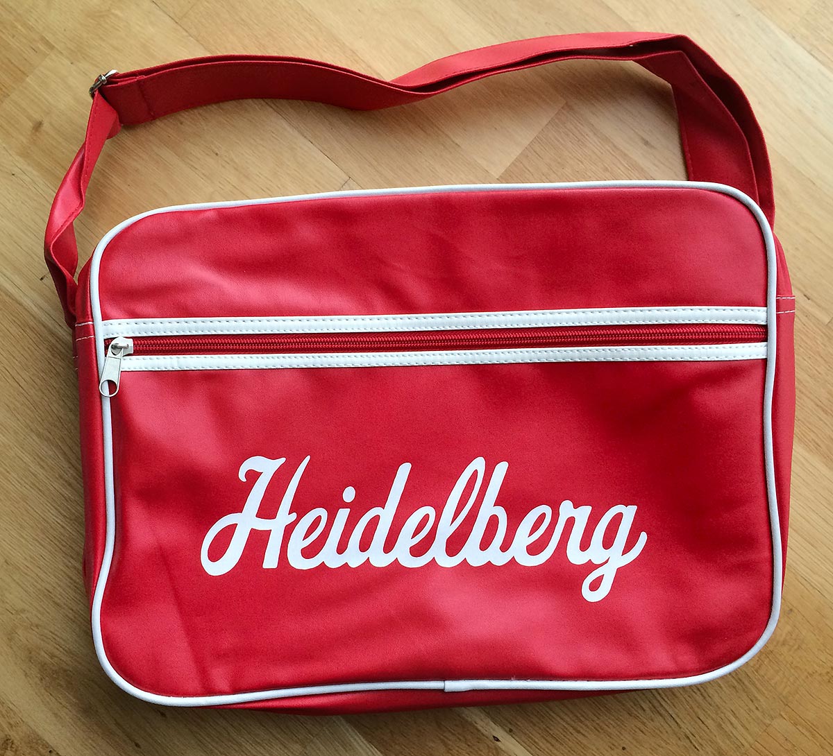 Reklamní červená retro taška přes rameno s bílým potiskem nápisu Heidelberg