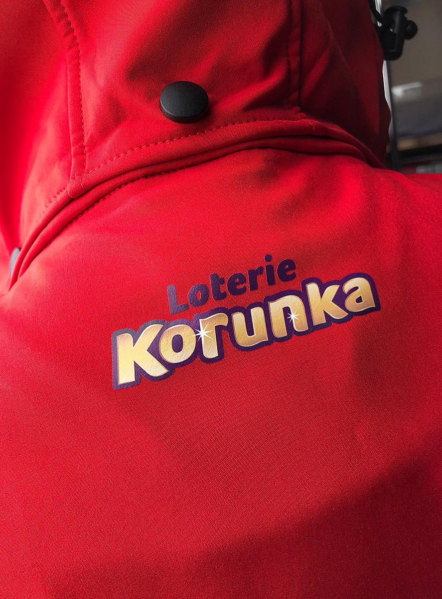 Reklamní červená softshellová bunda s potiskem loga Loterie Korunka