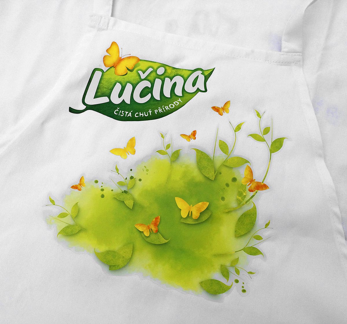 Reklamní bílá kuchyňská zástěra s barevným potiskem loga Lučina