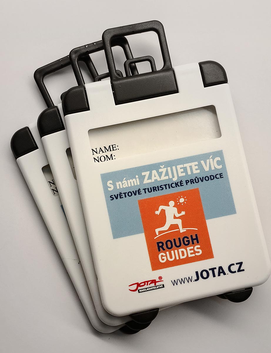 Reklamní bílé jmenovky na zavazadla s potiskem Rough Guides a logem nakladatelství Jota