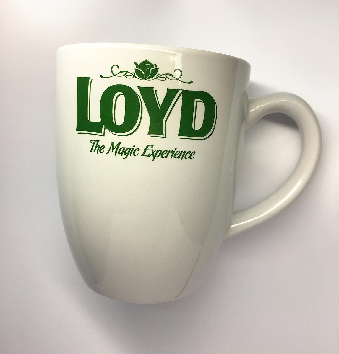 Reklamní bílý keramický hrnek se zeleným potiskem loga Loyd The Magic Experience
