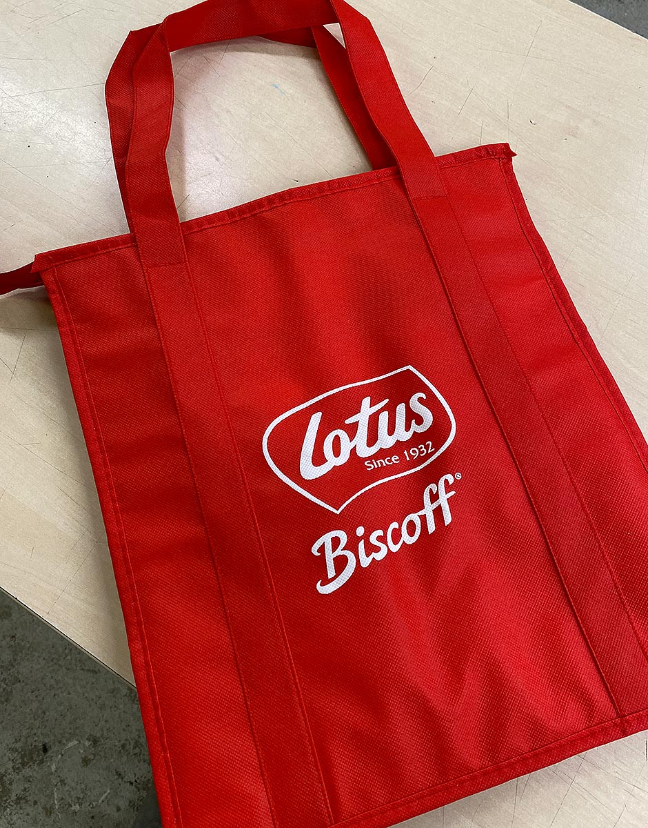 Reklamní červená nákupní taška z netkané textilie s potiskem loga Lotus Biscoff